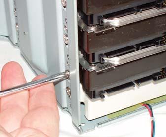 Slide the four hard drives into the drive bay and secure each of them with four screws (drive bay fan cable visible at bottom)
