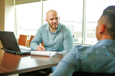 A photo shows an agent in a discussion with a man in the office.