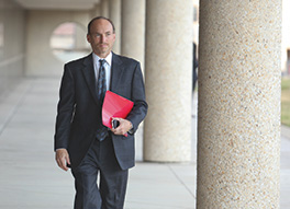 A photo shows a man walking with a red file in hand.