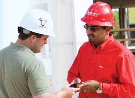 A photo shows two men wearing engineering caps discussing.