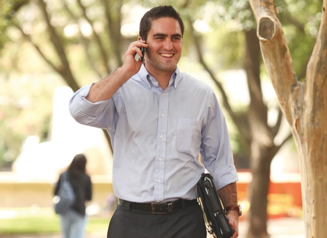 A photo shows a man walking while talking on a cell phone.