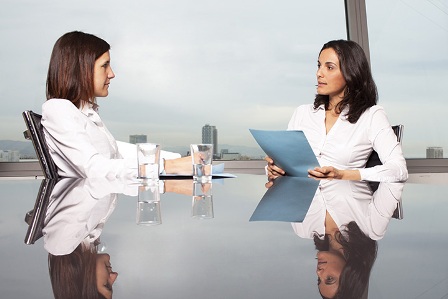 A photo shows two women involved in a discussion. One of them is holding a file.
