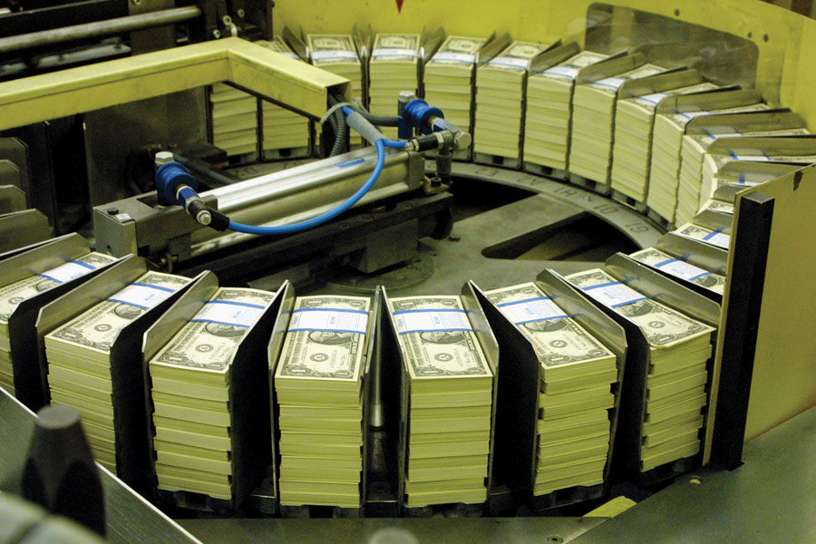 Photo shows a machine with a circular formation of slots that hold bundles of dollars.