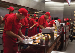 Photo shows people working in a commercial kitchen.