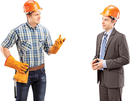 Photo shows Daniel and Stefan wearing construction helmets and talking to each other.