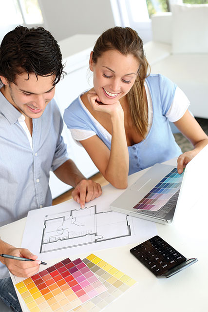 Photo showing a man and a woman drawing a plan and referring color palettes on a desk.