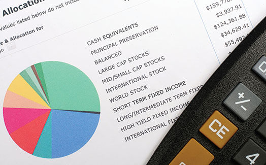 An image shows a calculator placed on a paper with a pie chart depicting details about varied investment opportunities.