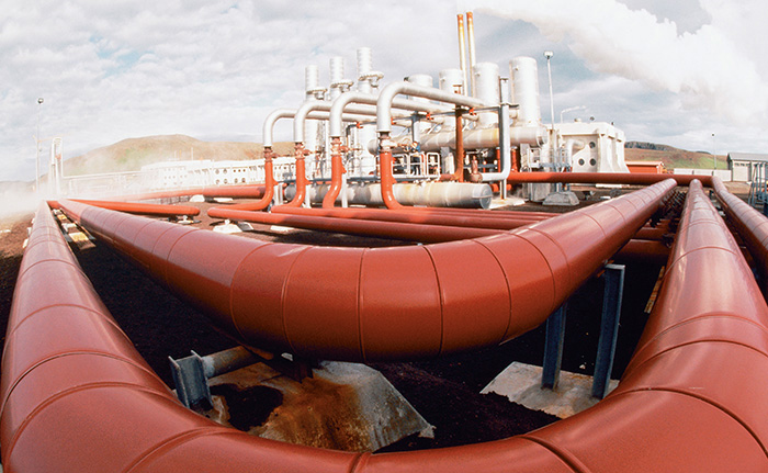 Photograph shows a thermal energy plant in Iceland consists of large red pipes toward the horizon.