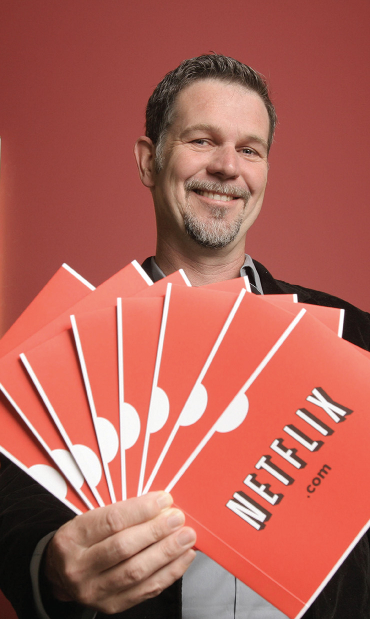 A photo of a person holding a fanned out group of Netflix D V D's in their hand.