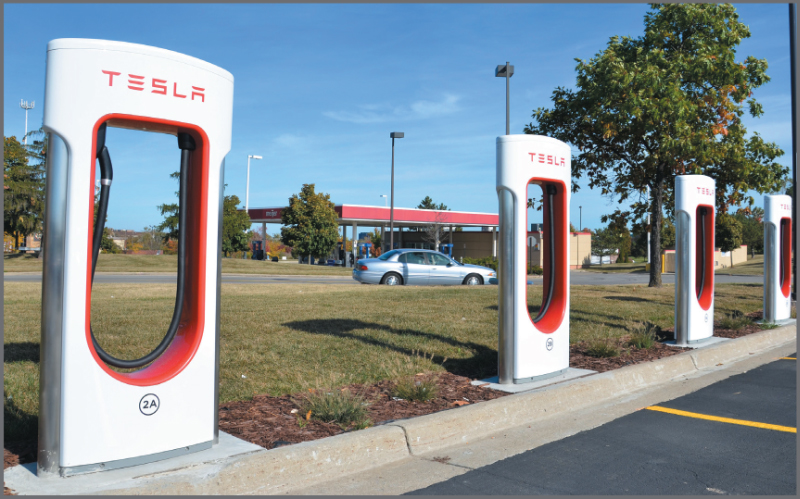 A photo shows Tesla’s battery charging station and a car standing beside it in a showroom.