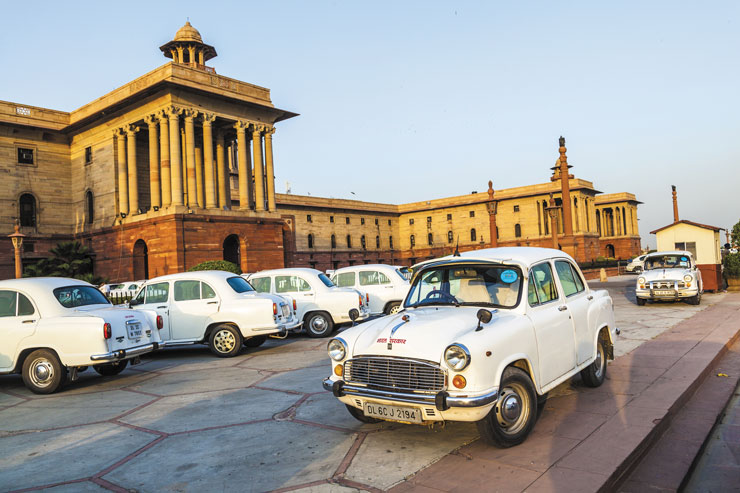 A photo of a side view of the Parliament Building in New Delhi, India, with several cars parked in the parking lot.