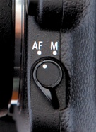 On the D90 body, just below the lens release button is a switch for changing between auto and manual focus.