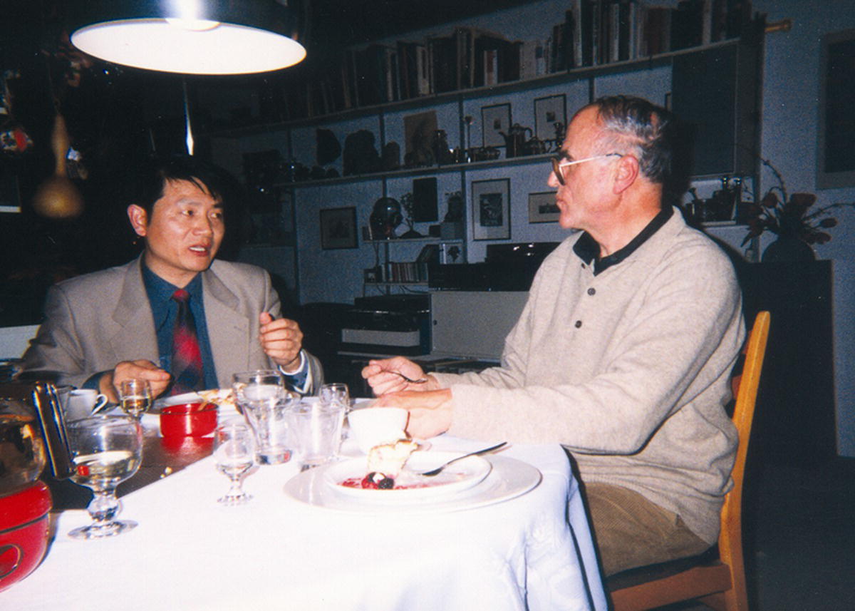Photo of Professor Xiaoting Rui (left) and Professor Jens Wittenburg (right) sitting along the table, facing each other.