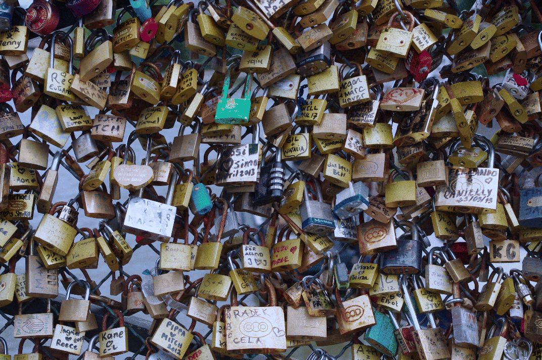 A photograph depicting various love padlocks locked to a fence.