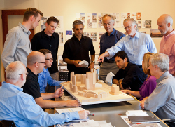 Photograph of Jeffrey Painea discussing with a group of men, focusing on the contributions of clients, design team members, and other experts.