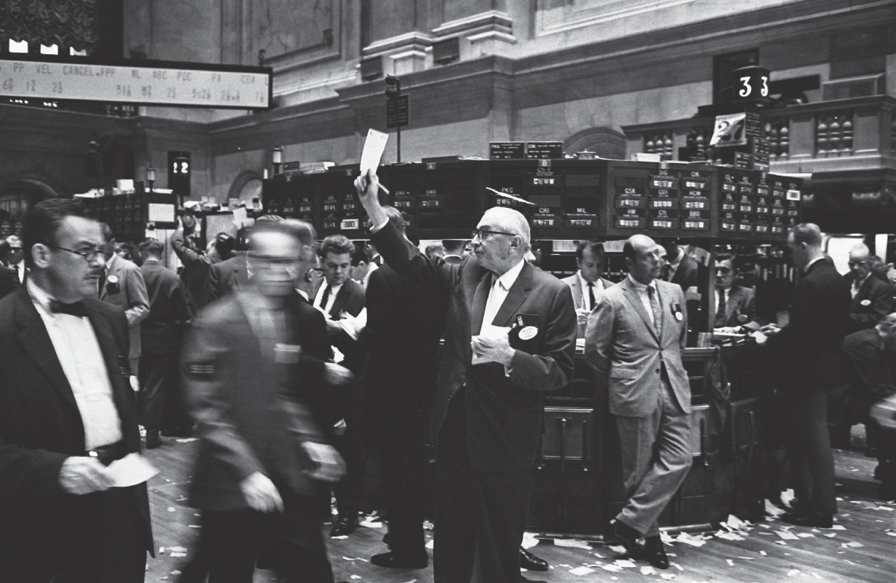 Photograph of a financial stock market scenario with a group of traders shouting at each other to execute trades.