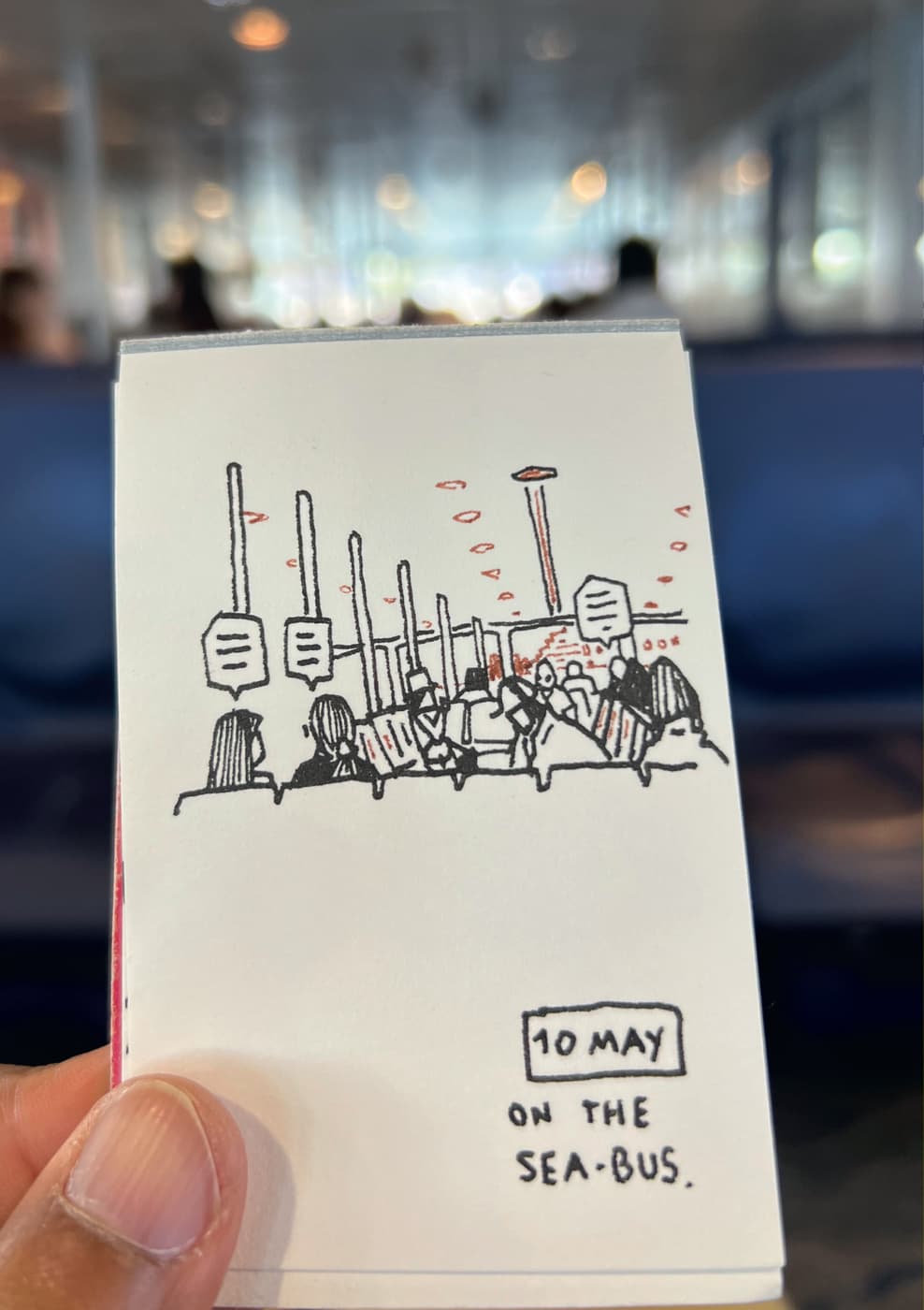A hand-drawn sketch of passengers seated on the sea bus, with poles, signs, and a distant view of the ferry interior, '10 May.'
