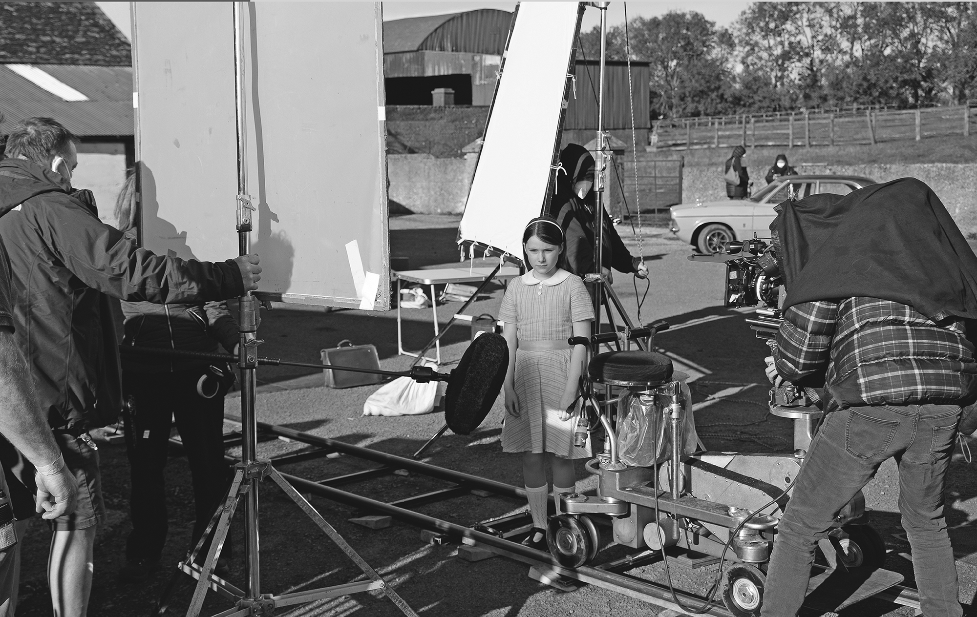 Two photos present film production scenes, depicting a crew filming on a dock at sunset, while another scene depicts a rural set with lighting and a child actor.