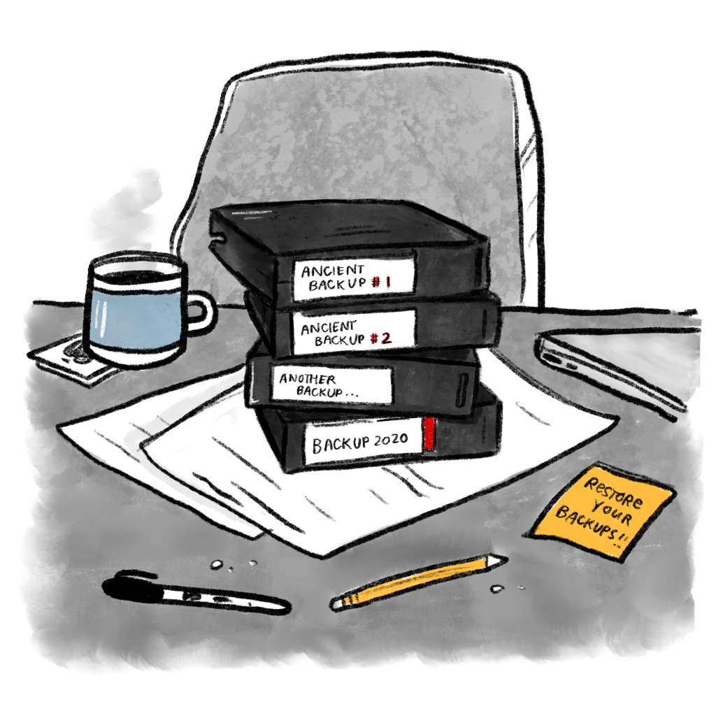 A pile of four tape backups labeled 'ancient backup #1' through 'backup 2020' sits on top of papers on a messy desk. A post-it note nearby reads 'restore your backups!'